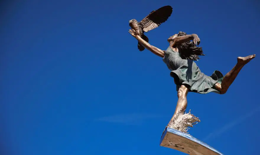 statue of a girl running with an owl on her arm